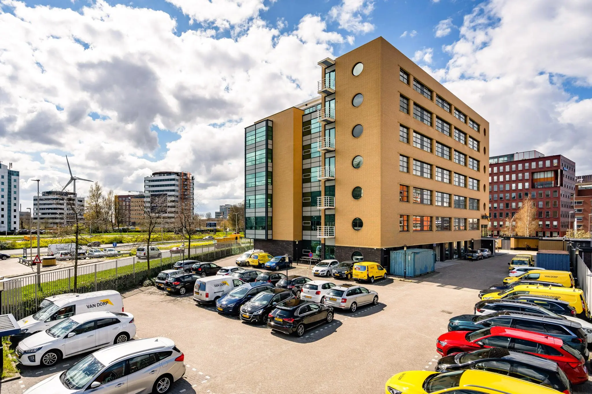 Kantoorgebouw aan de Fascinatio Boulevard met aangrenzend parkeerterrein vol auto's en bestelbussen.